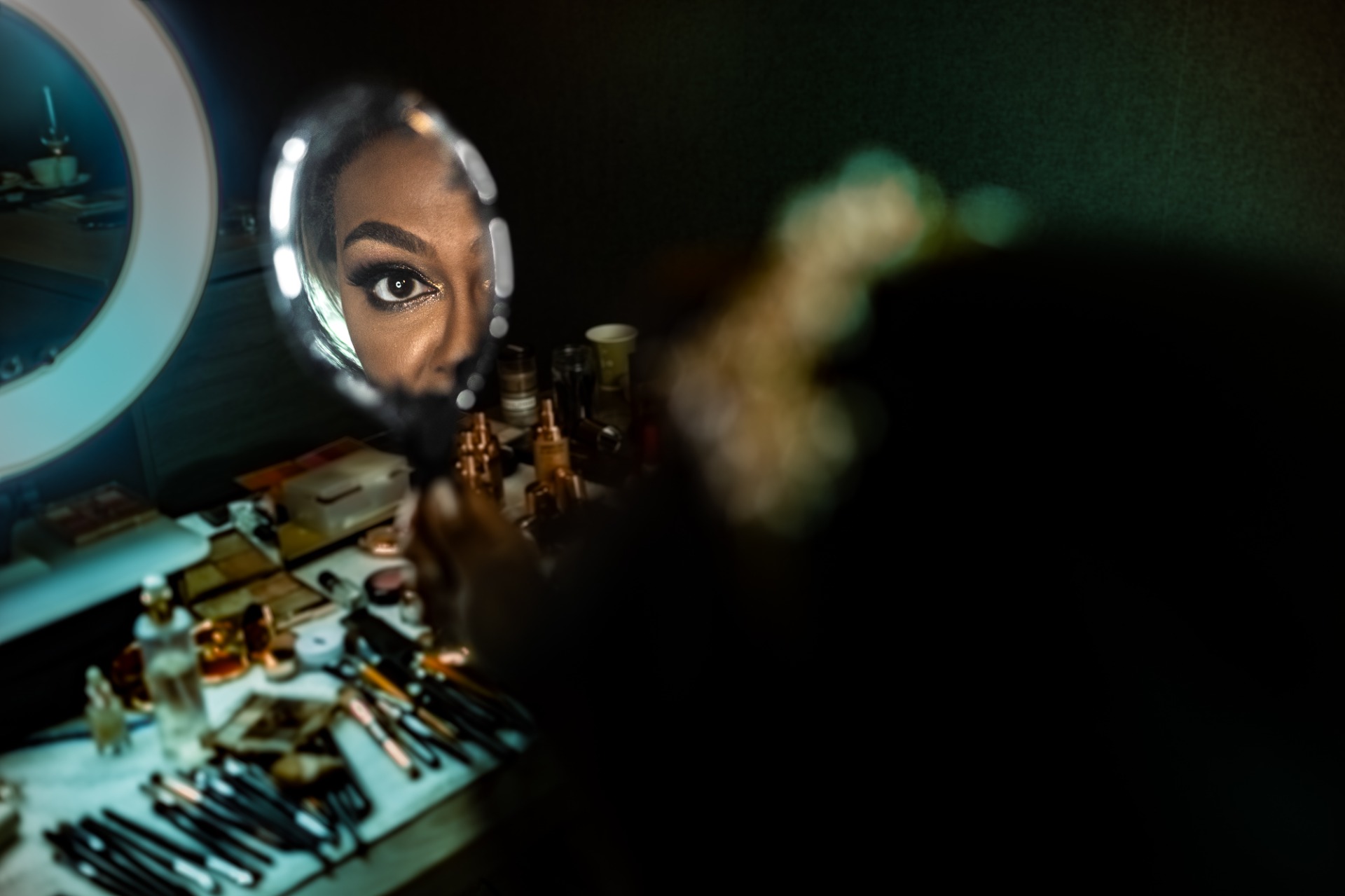 Close-up van een vrouw met make-up, gefotografeerd via vergrootglas, met gereedschap en cosmetica op tafel.